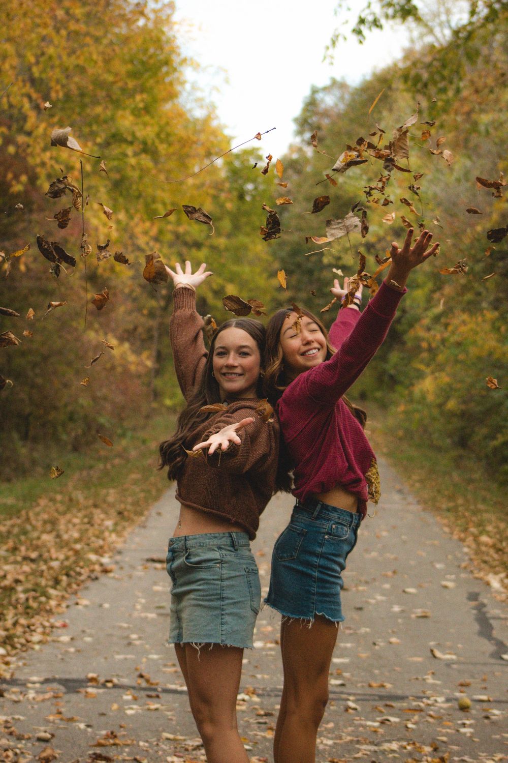 two friends throwing leaves in the air