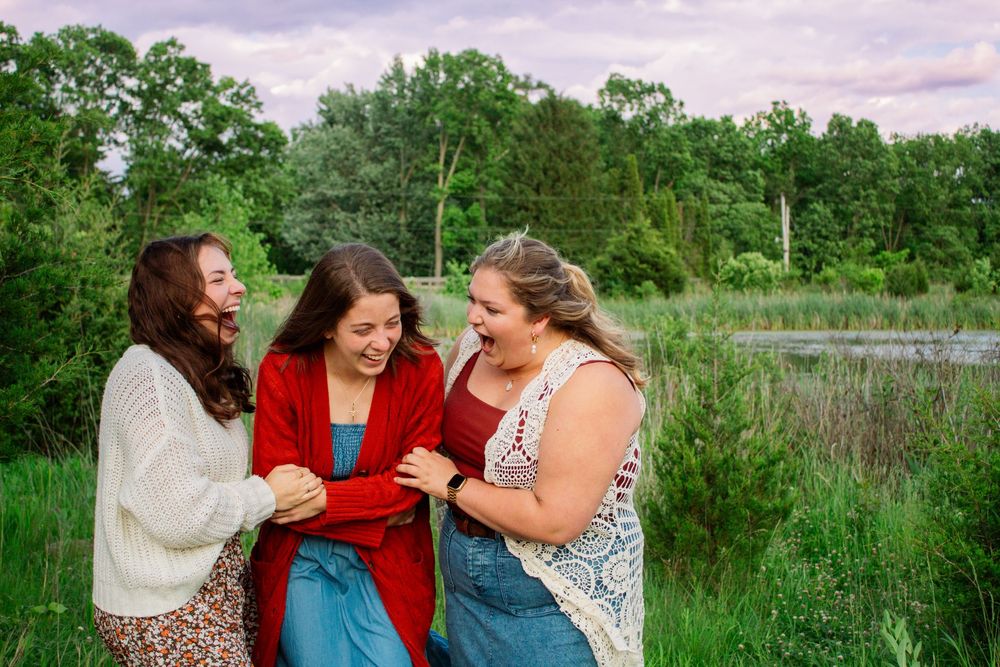 three friends laughing in a green park