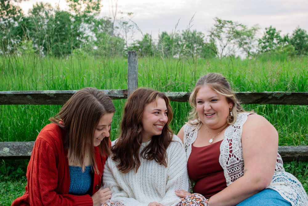 Three friends sitting in front of an old fence