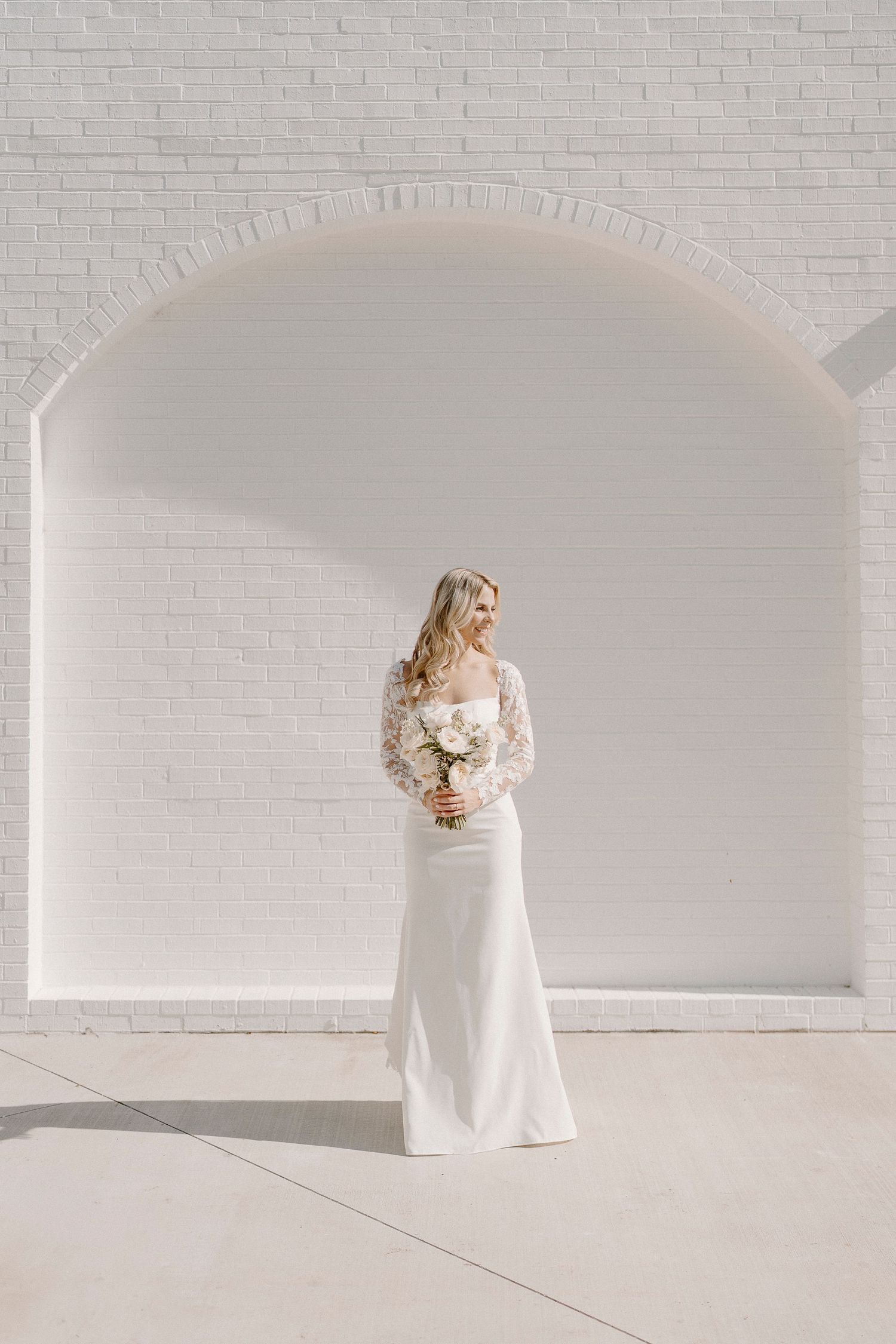 A bridal photo against clean white brick walls and arched architecture at The Grand at Willow Springs.