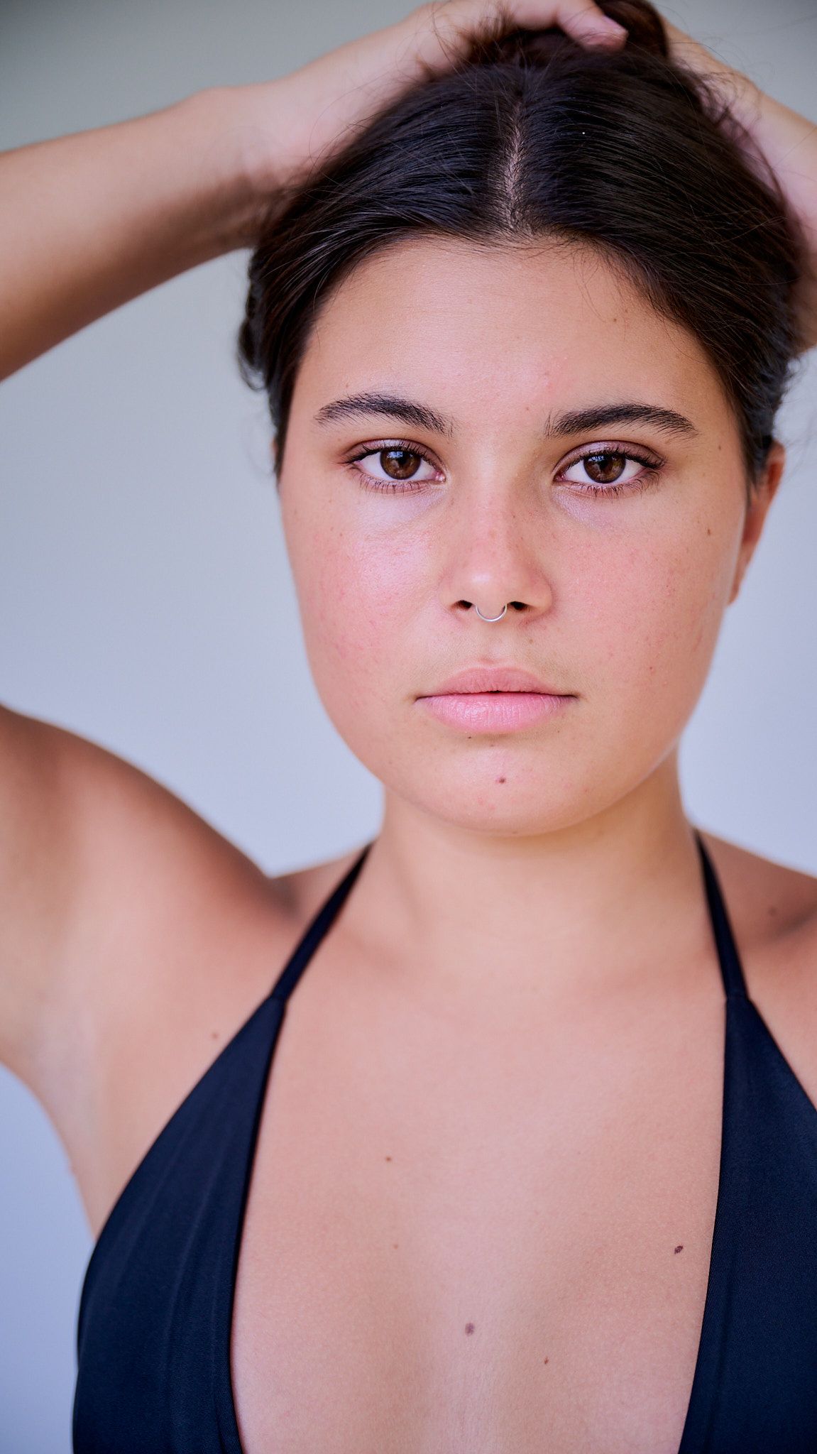Model poses in white crop top and denim against light blue background in series of artistic fashion shots.