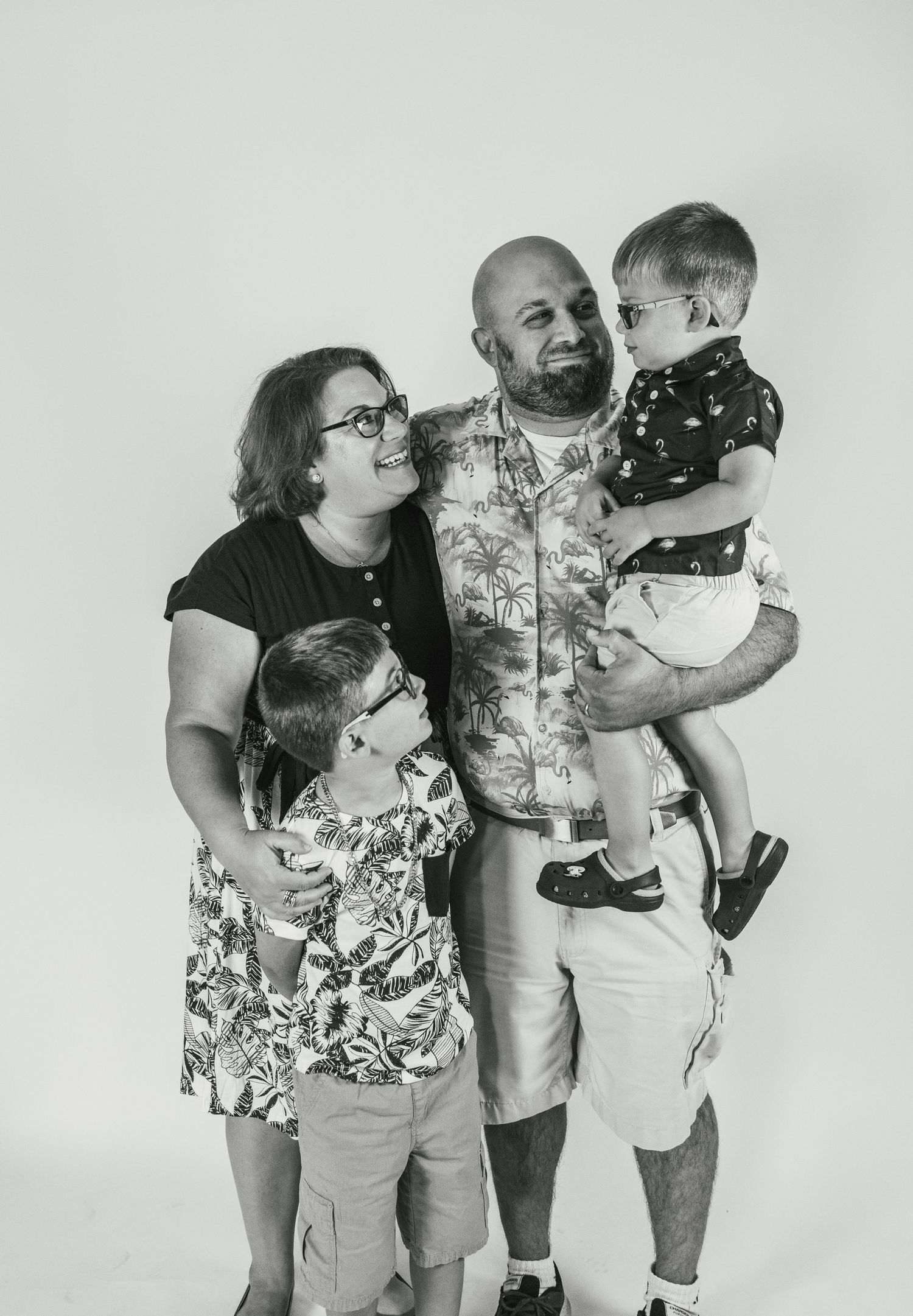 A black and white photo sequence showing playful family interactions and embraces against a plain background.