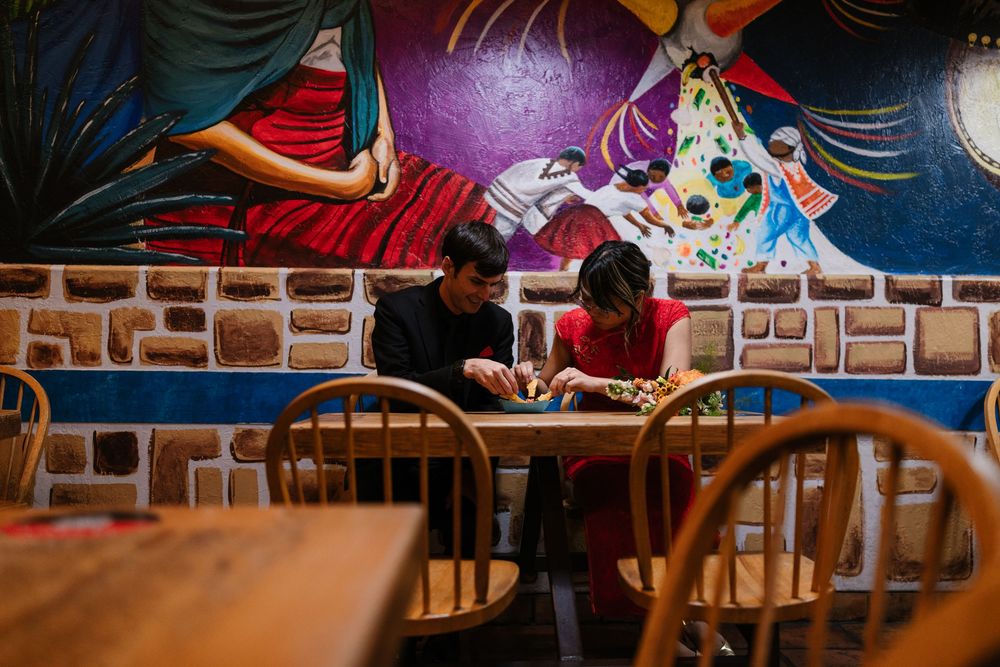 A row of wooden chairs at a restaurant with colorful wall art and murals in the background.