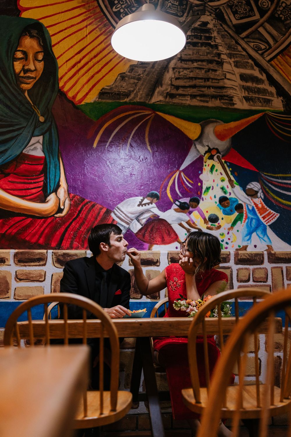 Students studying together at wooden tables in a cozy restaurant interior with warm lighting and brick walls.