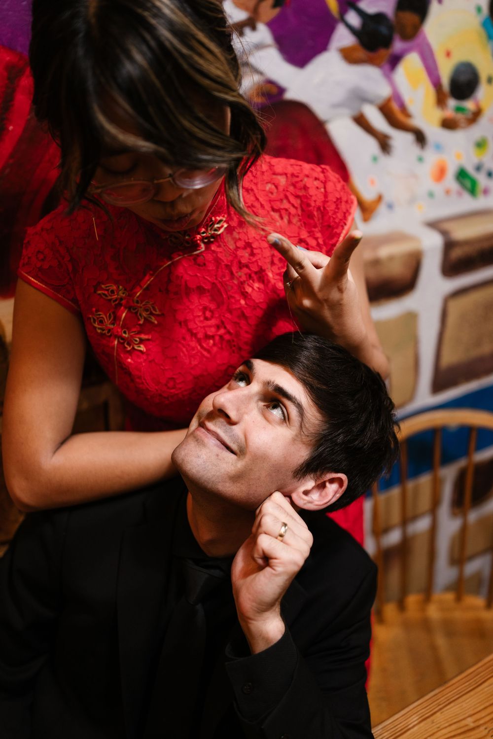 A couple shares a playful moment as they lean in close to each other at a social gathering.