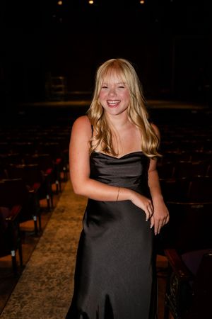 A series of photos showing a person in a black dress smiling and posing in a dimly lit theater setting.