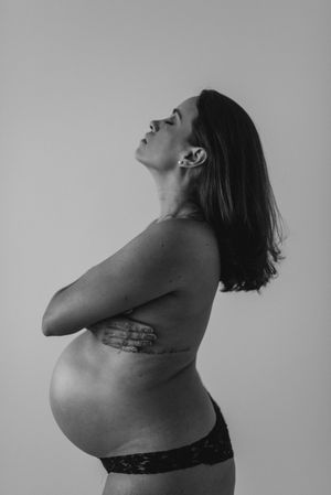 Side profile of pregnant woman in artistic black and white photography.