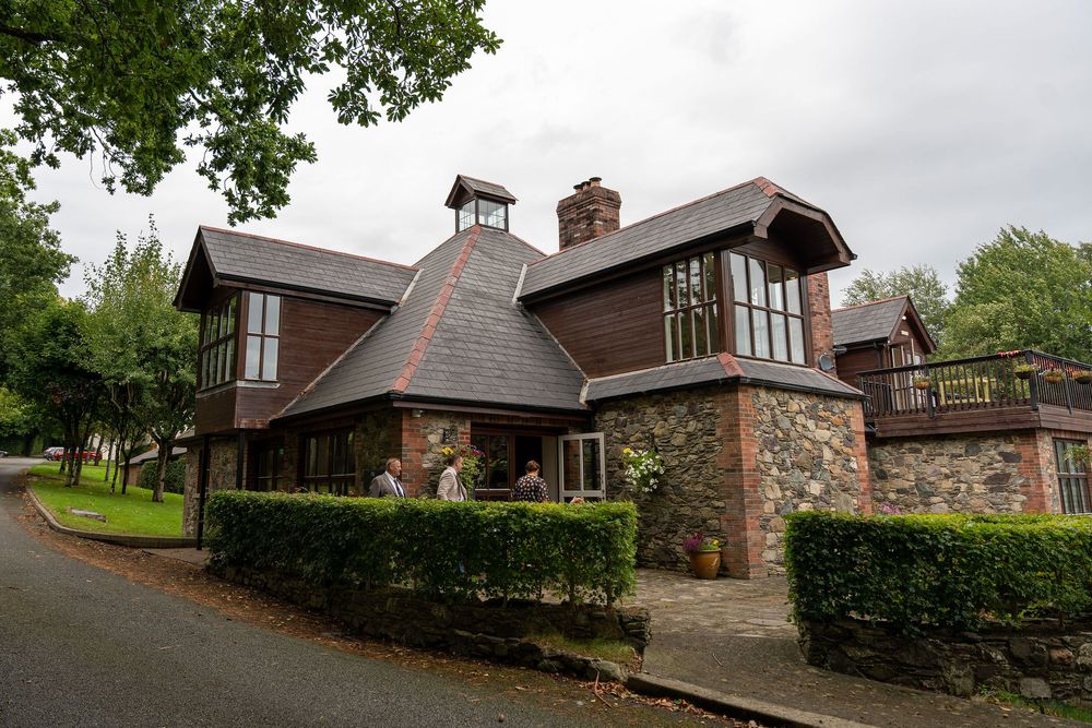 Panoramic view of traditional brick houses with pitched roofs and landscaped gardens along a winding residential street.