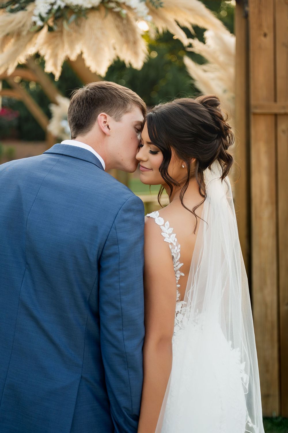 Intimate wedding portrait with couple sharing a tender moment against wooden backdrop.