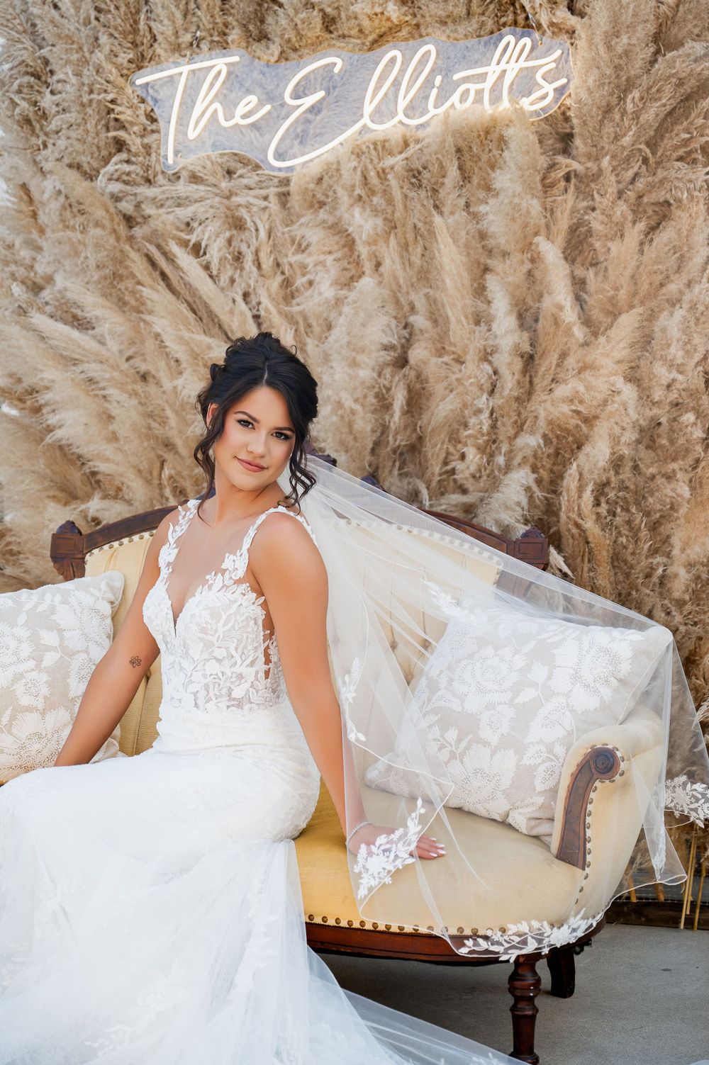 Elegant bridal portrait with lace dress against textured champagne backdrop.