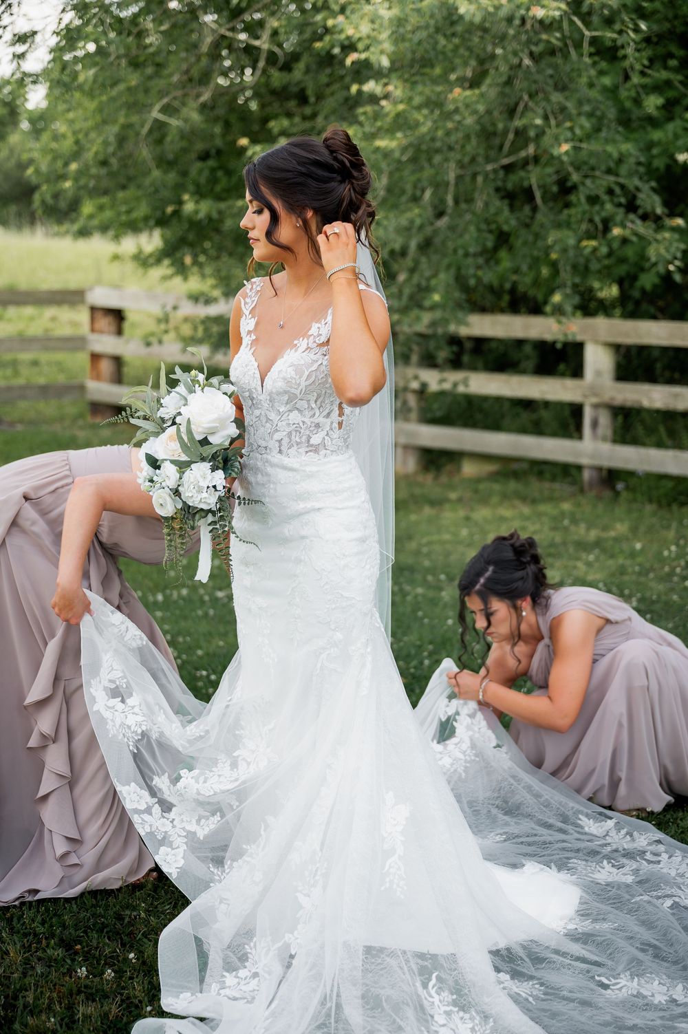 Elegant white lace wedding dress with flowing train photographed in outdoor garden setting.