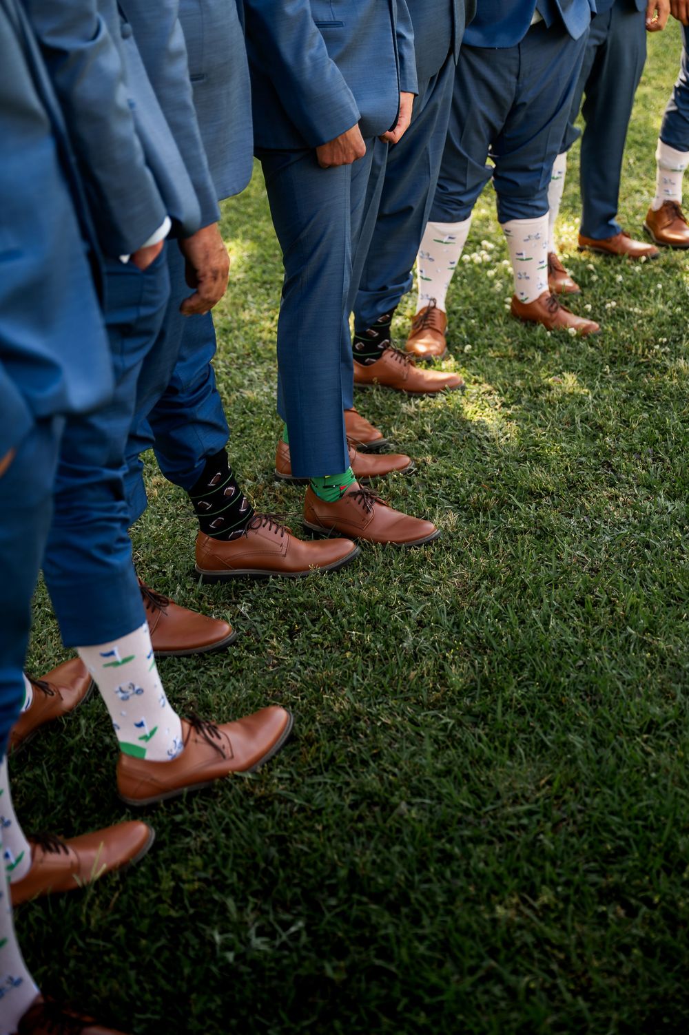 Row of groomsmen's feet showing brown dress shoes and fun patterned socks.