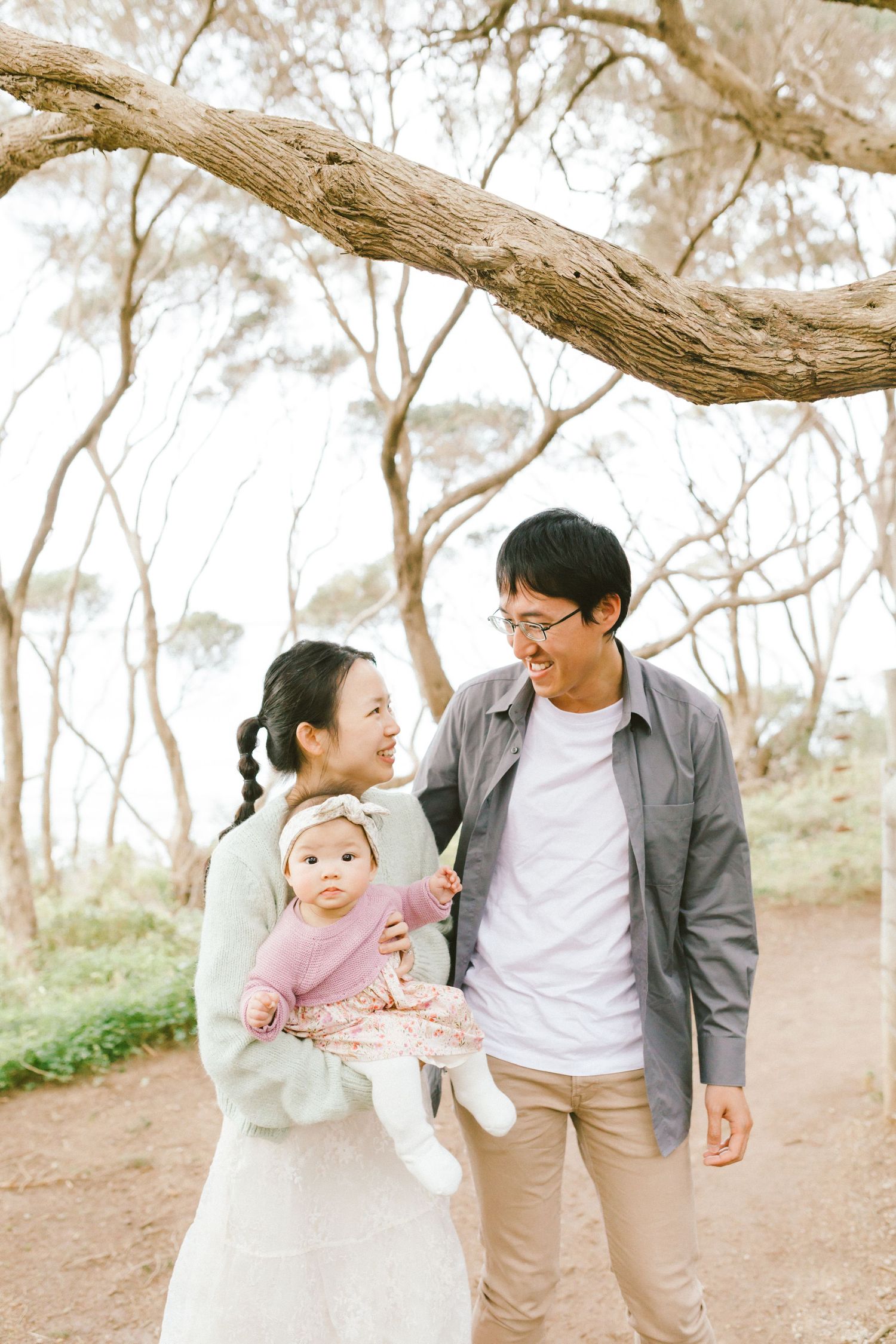 A family walks together and shares joyful moments along a tree-lined path on a bright sunny day.