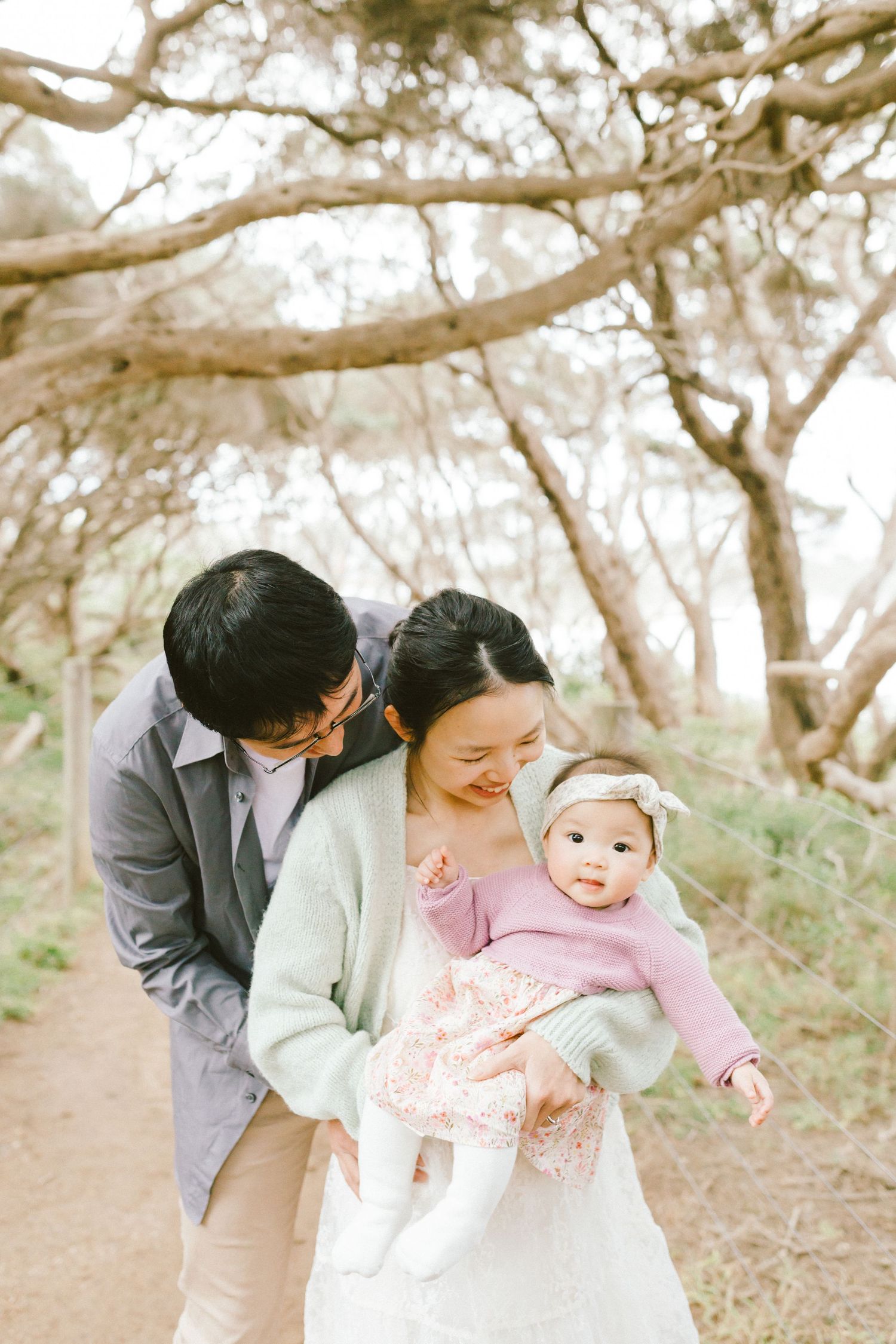 A family enjoying a tender moment together while walking through a scenic wooded area on a bright day.
