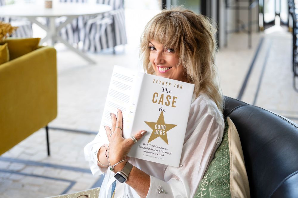 Someone holds up a book with a star design while sitting in a modern interior setting with yellow furniture.