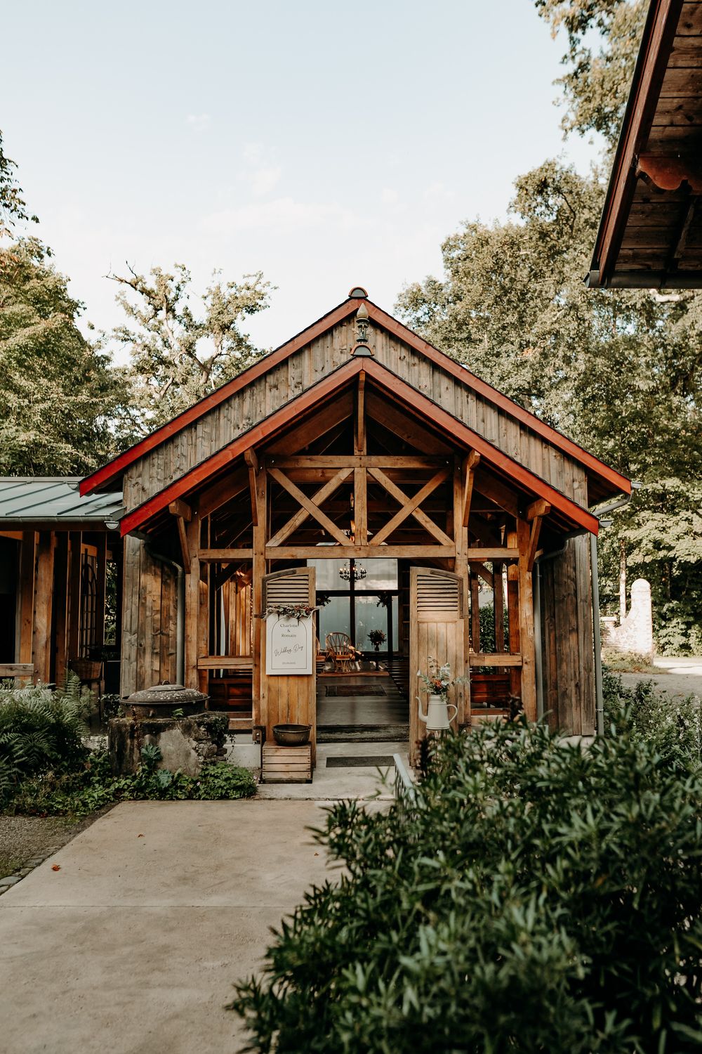 Rustic wooden lodge venue with exposed timber beams and stone accents surrounded by lush greenery.