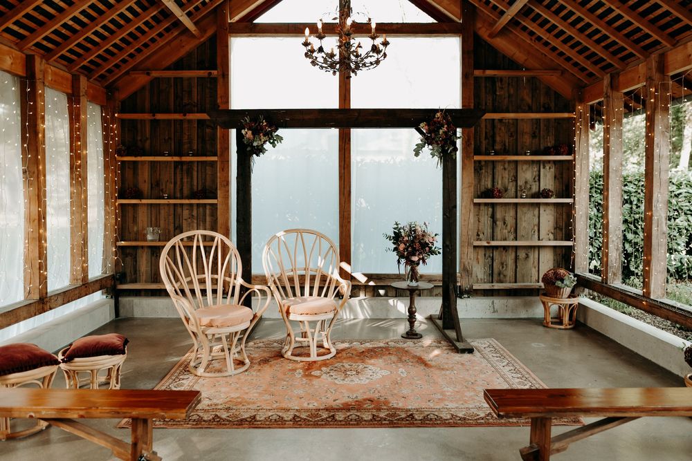 A rustic wooden porch with rocking chairs and exposed beams overlooks a serene outdoor view.