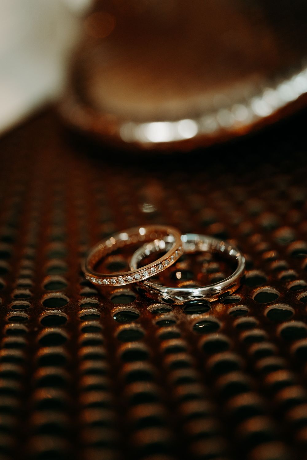 Close-up macro shot of wedding rings with textured background creating artistic bokeh effect.