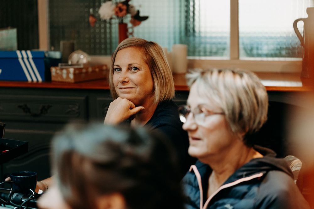 A person in a classroom setting speaks into a microphone while others listen attentively during a presentation.