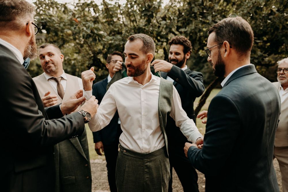 Group of wedding guests in formal attire gathered together for celebration outdoors.