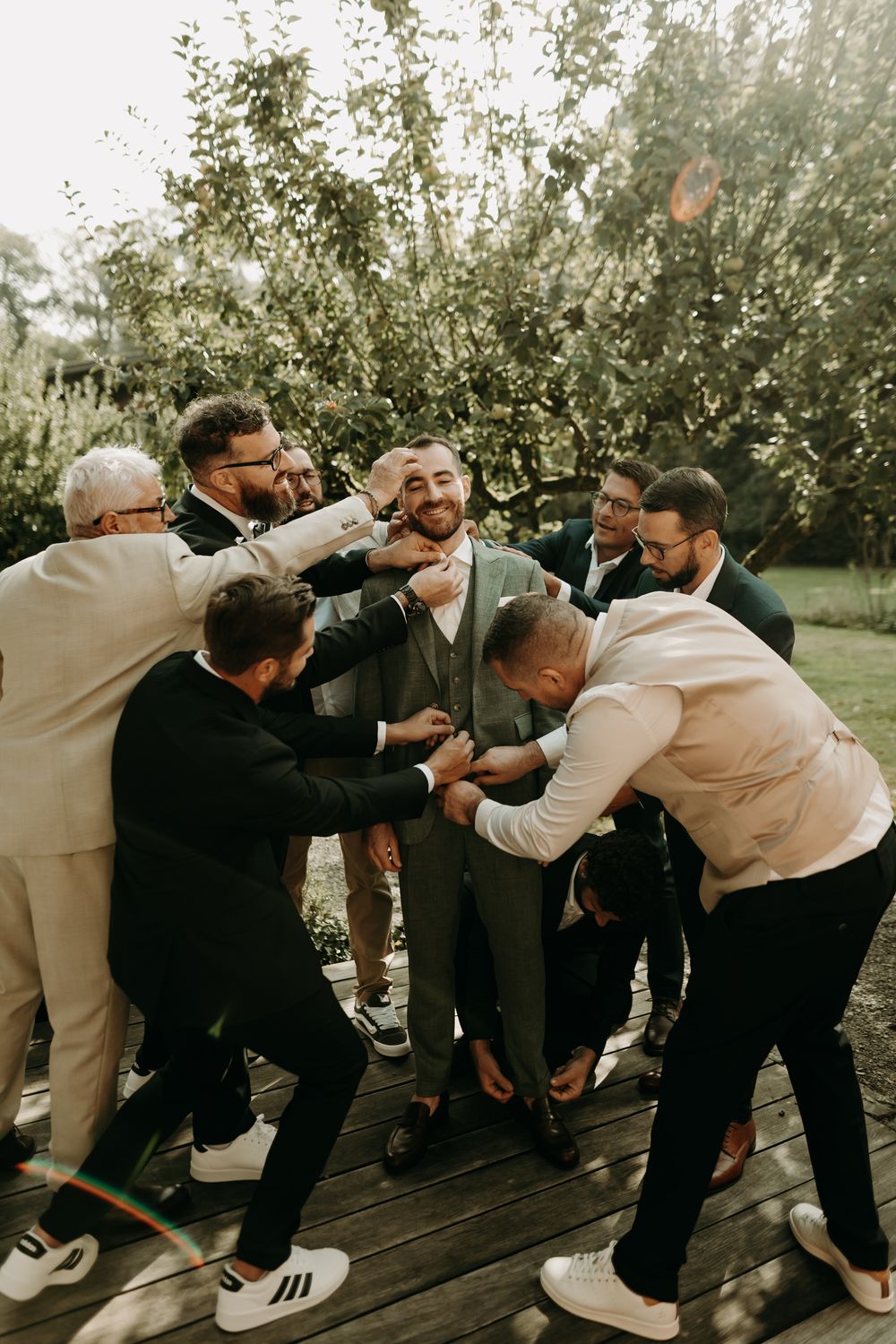 Groomsmen playfully posing and leaning on each other in a fun group photo outdoors.