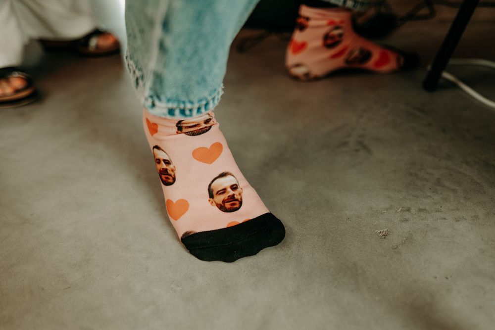 Couple's feet wearing colorful socks and sneakers on a concrete floor at a wedding.