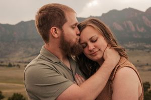 A romantic couple embraces in front of a scenic mountain landscape during golden hour. | Motherhood + Family Photographer Westminster, CO