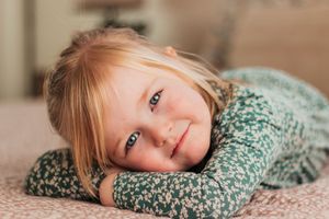 girl wearing a green floral dress lies on a wooden floor in a series of artistic poses. | Motherhood + Family Photographer Westminster,  CO