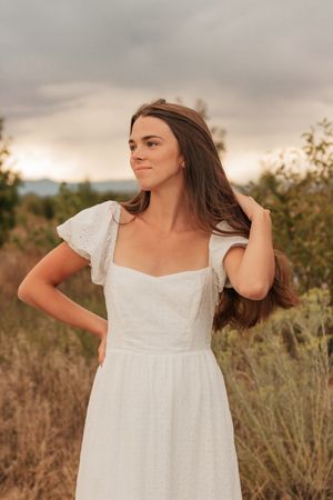 A woman in a white empire waist dress poses outdoors at sunset  | Motherhood + Family Photographer Westminster, CO