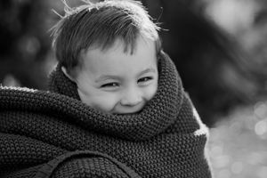 A black and white portrait  showing close-up views of a child with a blanket over him  | Motherhood + Family Photographer Westminster, CO