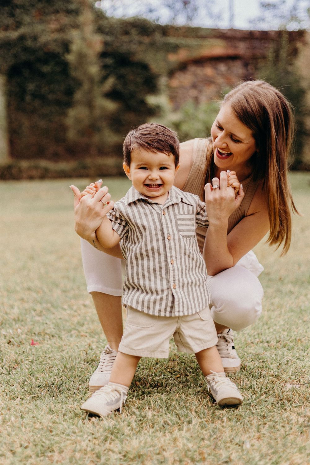A joyful outdoor moment between parent and child playing together on green grass in warm sunlight.