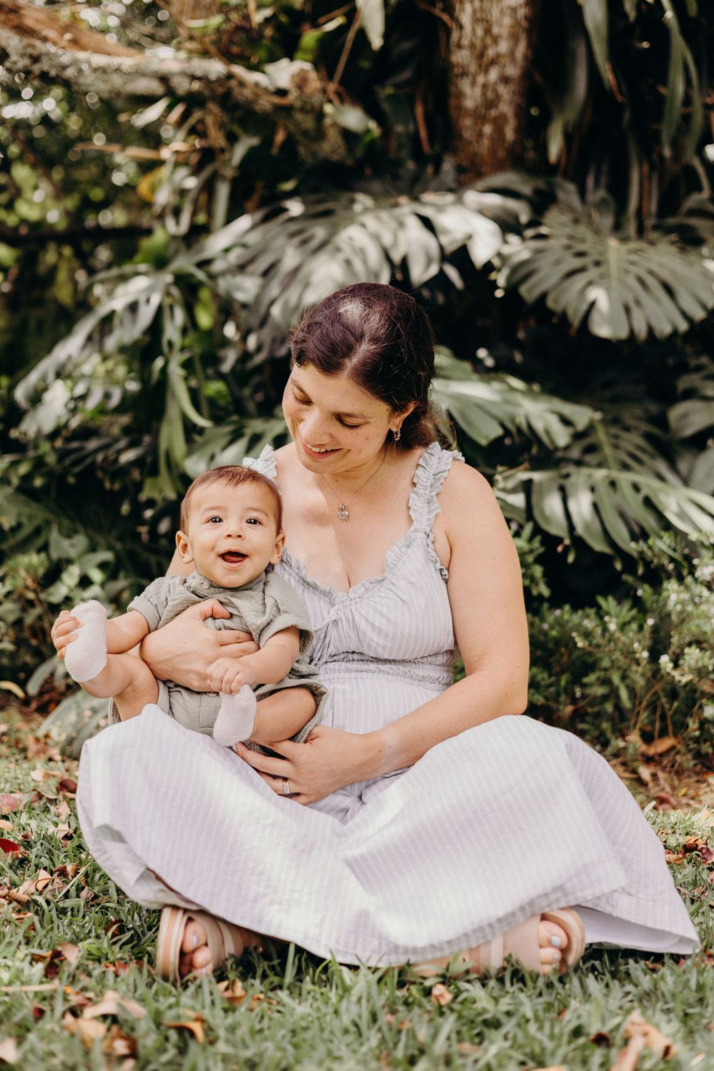 A tender outdoor portrait in a lush tropical garden with monstera leaves creating a natural backdrop.