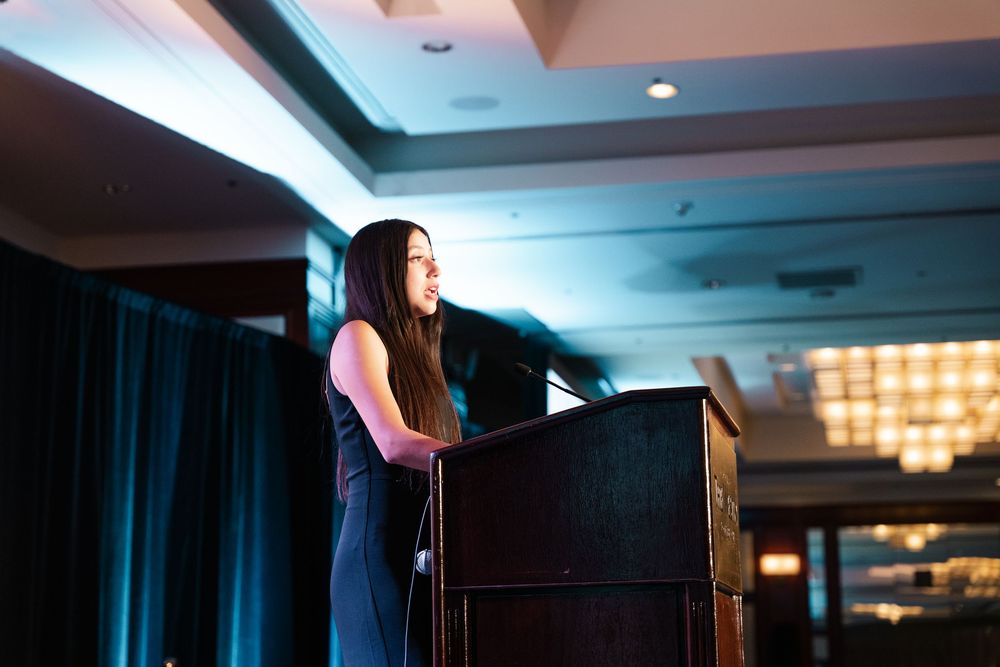 Woman in black dress speaks at podium during a professional conference at The Westin Long Beach.
