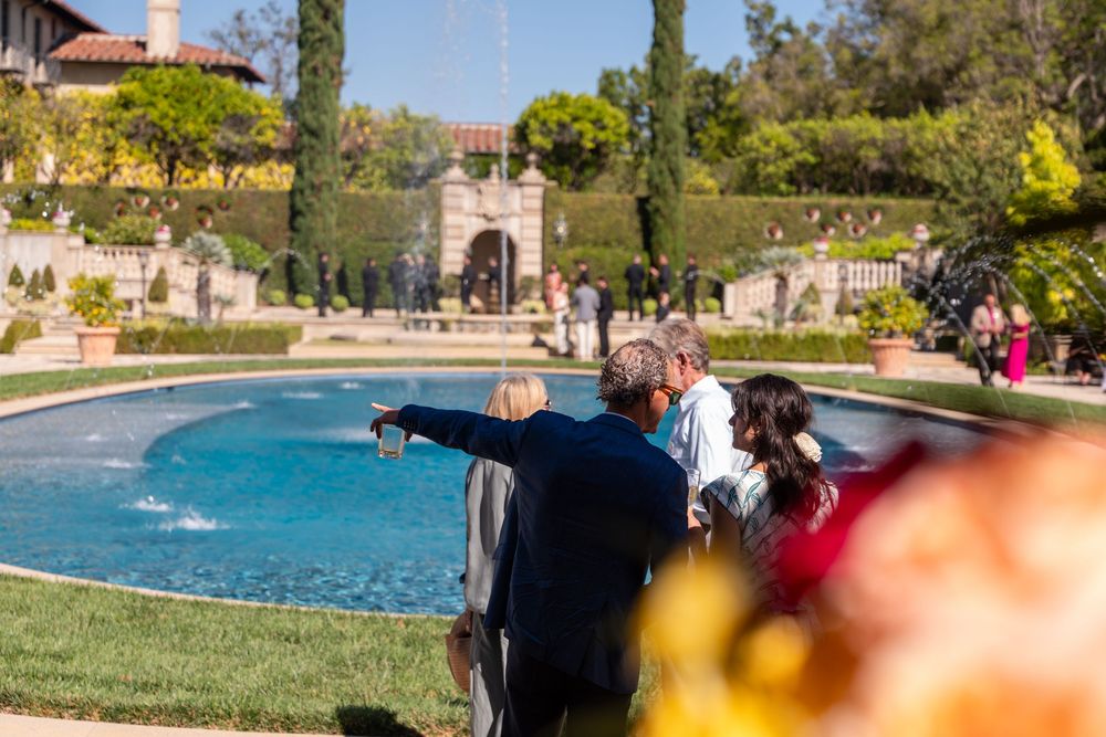 Guests admire a serene garden fountain surrounded by lush greenery at an elegant outdoor estate venue.