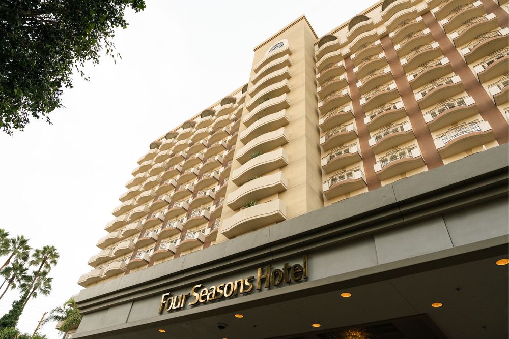 Modern high-rise apartment building with balconies and curved architectural details viewed from multiple angles.