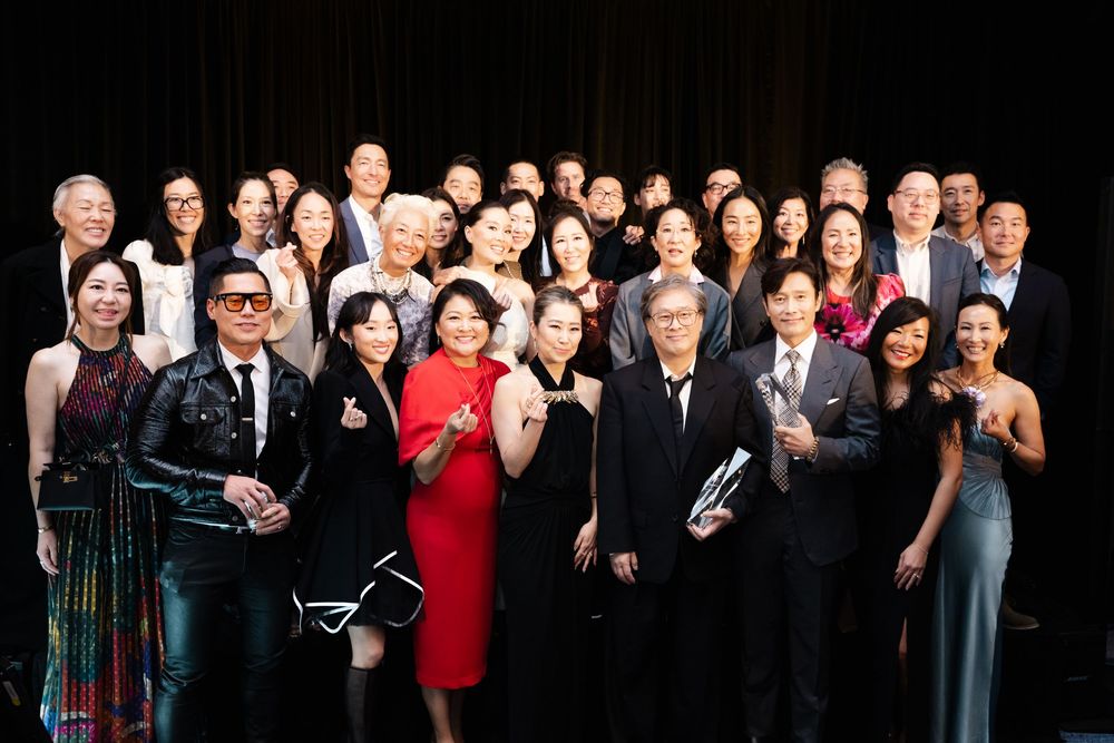 A large group of formally dressed people pose together in elegant attire at a special event.