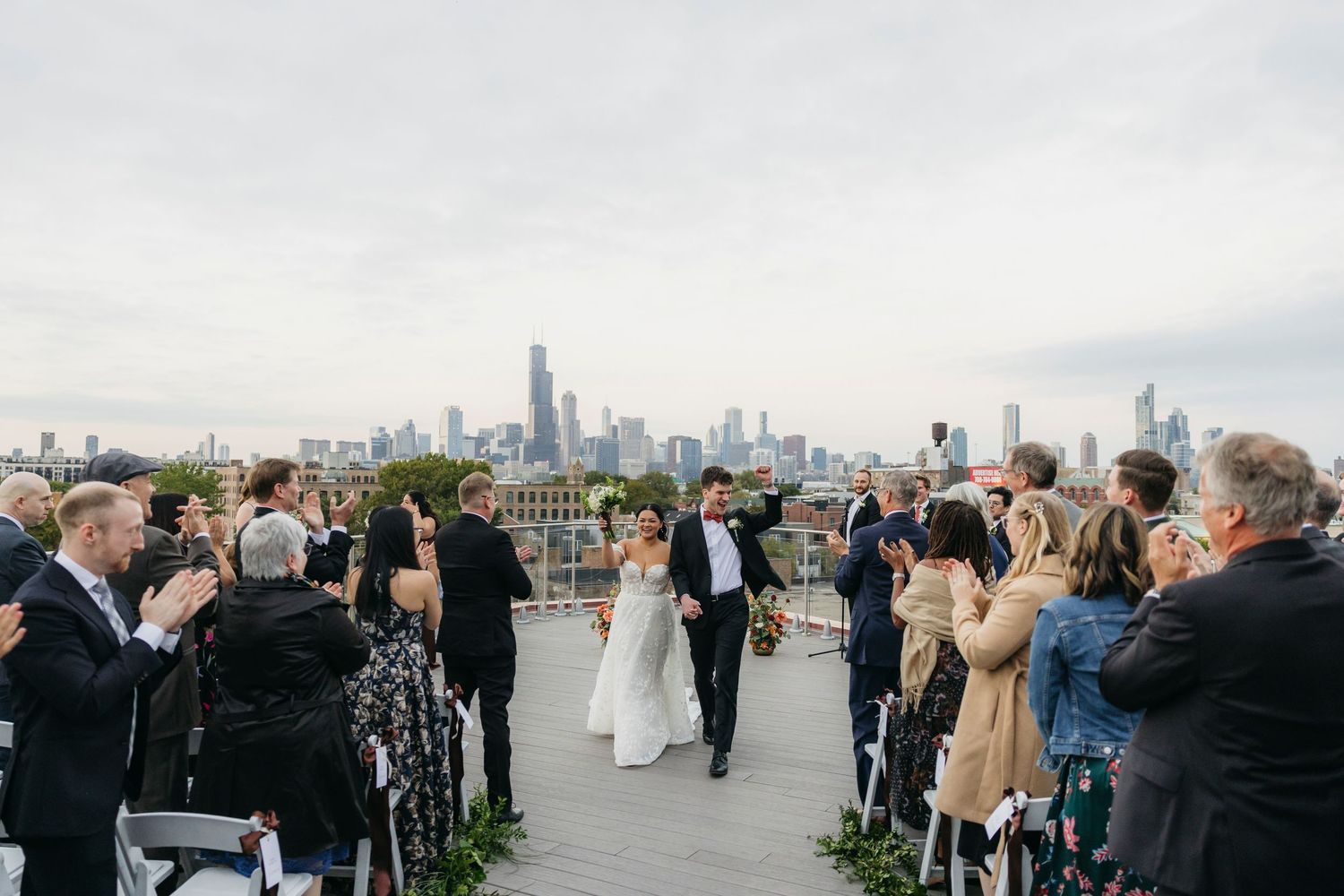 A couple shares a tender moment on a balcony overlooking a coastal landscape on their wedding day.