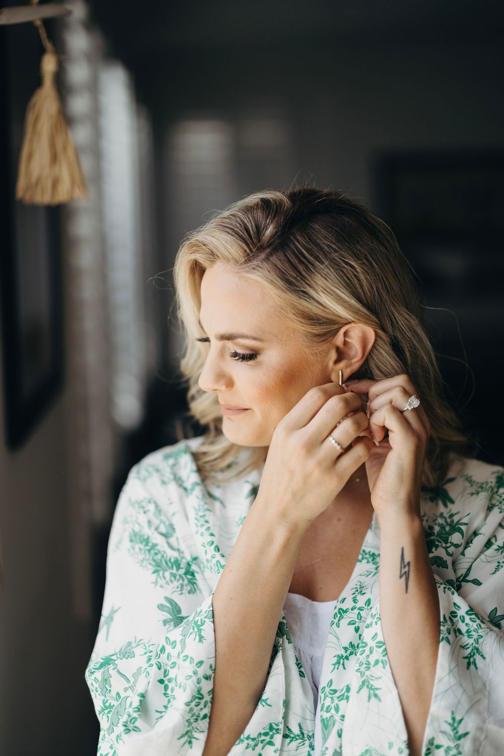 Close-up shots of someone putting on earrings while wearing a floral robe.