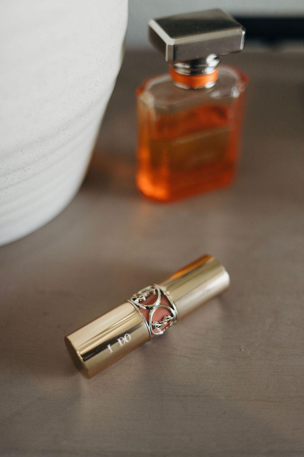 Luxury perfume bottles and gold lipstick cases arranged on dark wooden surface.