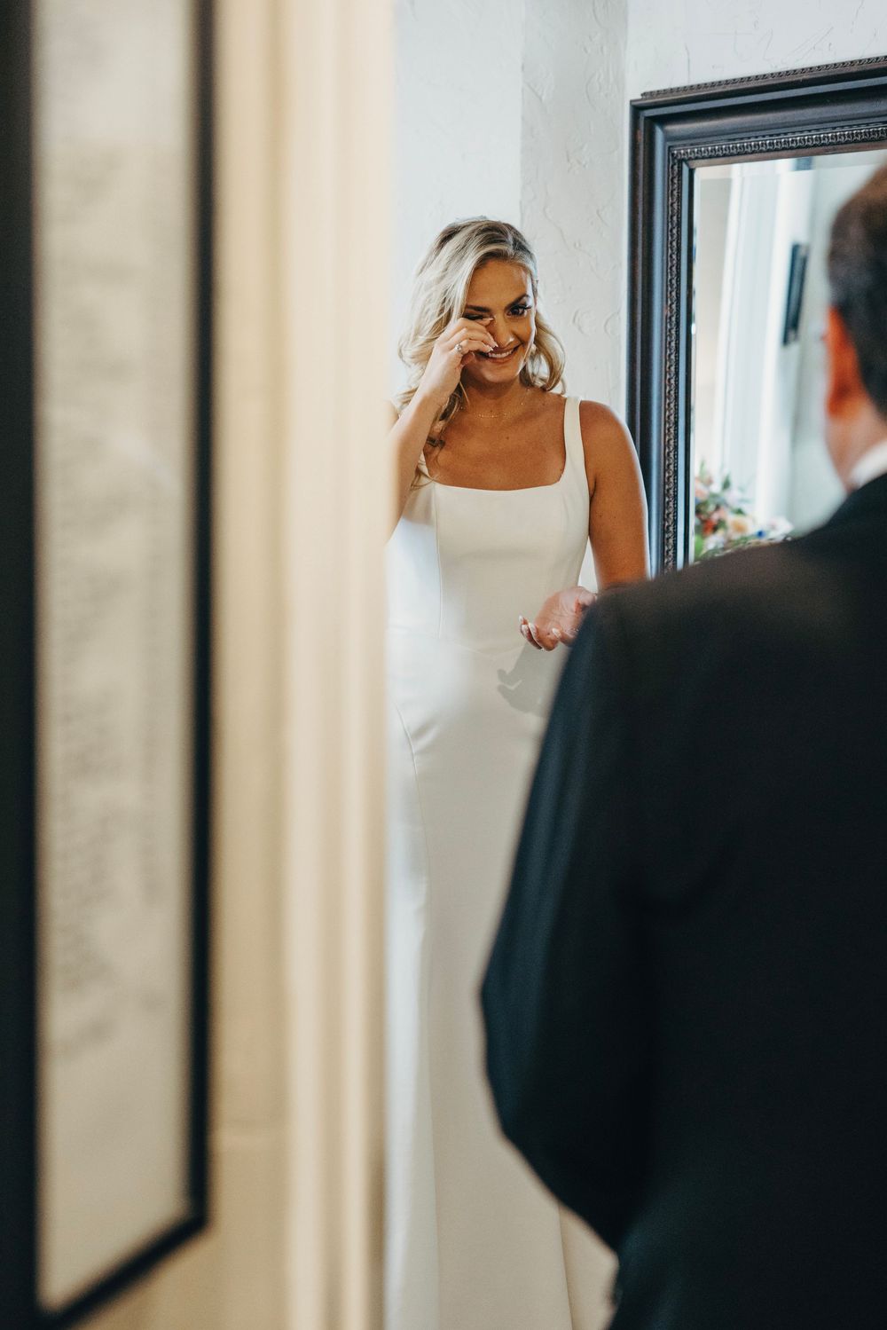 A reflection in a mirror shows a person in white getting ready for a special occasion.