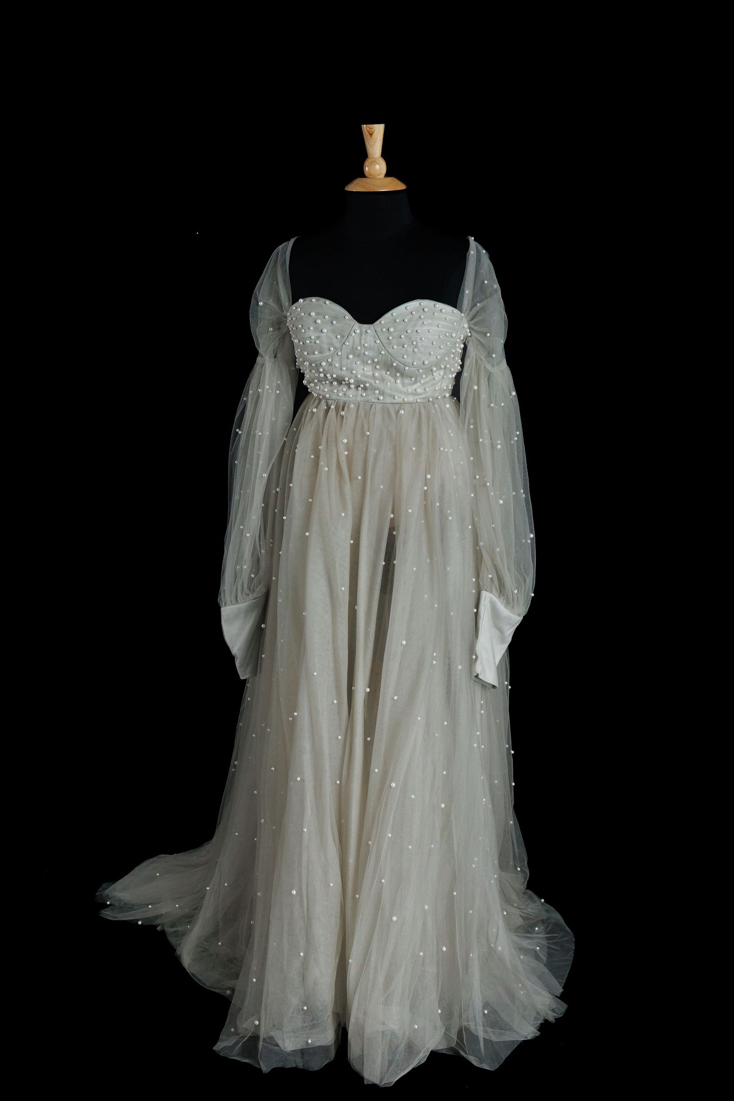 Light gray maternity gown with pearl beaded sweetheart bodice, sheer long sleeves, and flowing pearl-detailed tulle skirt on a dress form.