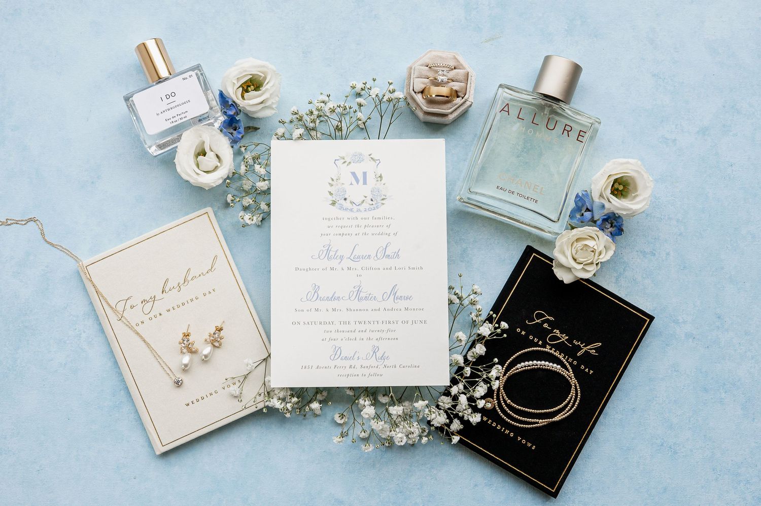 Wedding invitation suite with delicate jewelry and floral accents on light blue background.