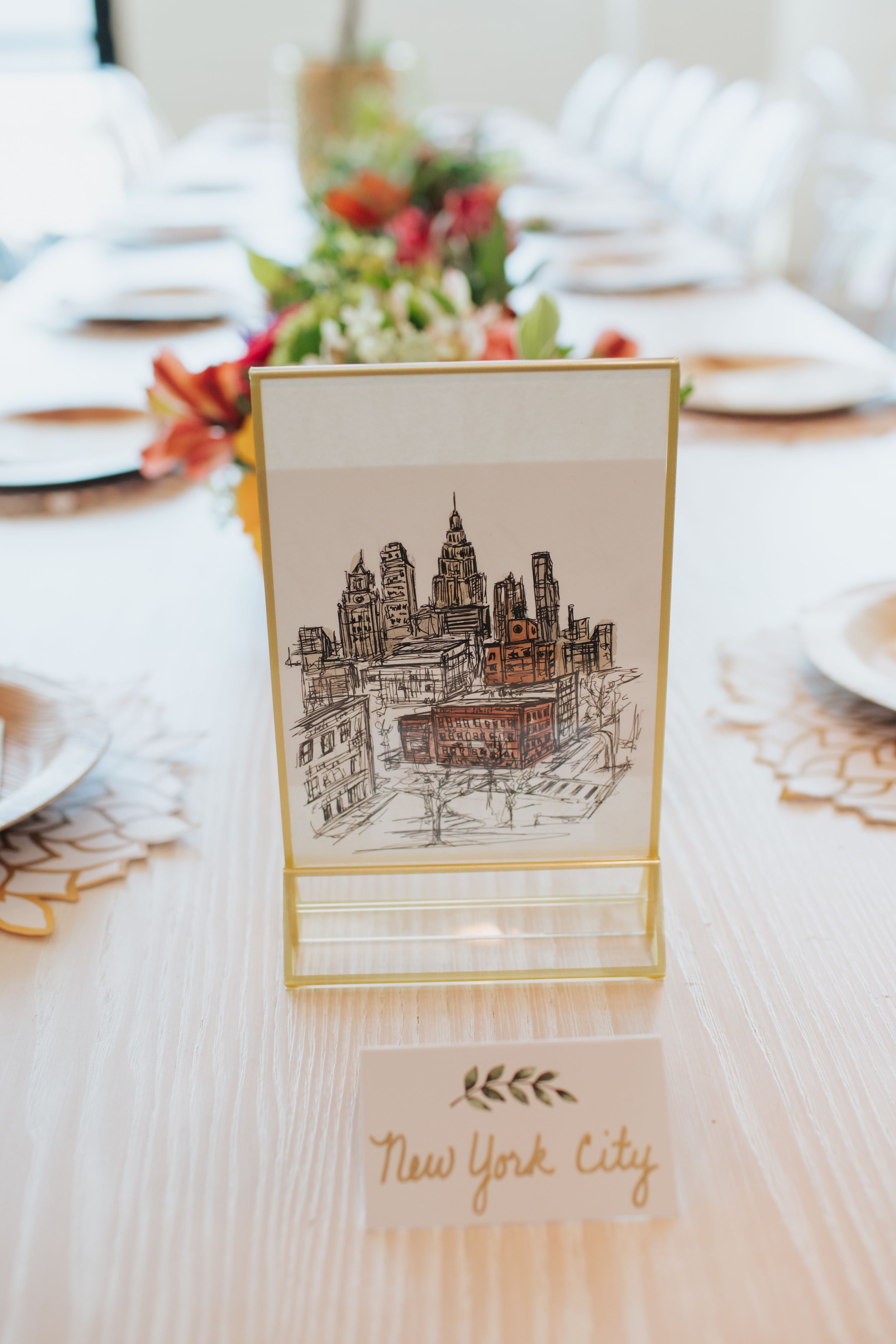 Elegant table setting with a New York City skyline illustration card display and floral centerpiece.