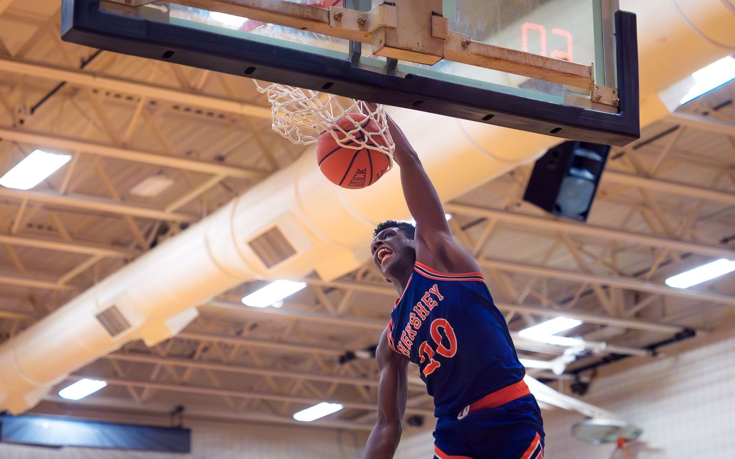 Drew Grana, Hershey High School Trojans dunks basketball at Palmyra High School basketball game in dark blue uniform with orange, Palmyra PA