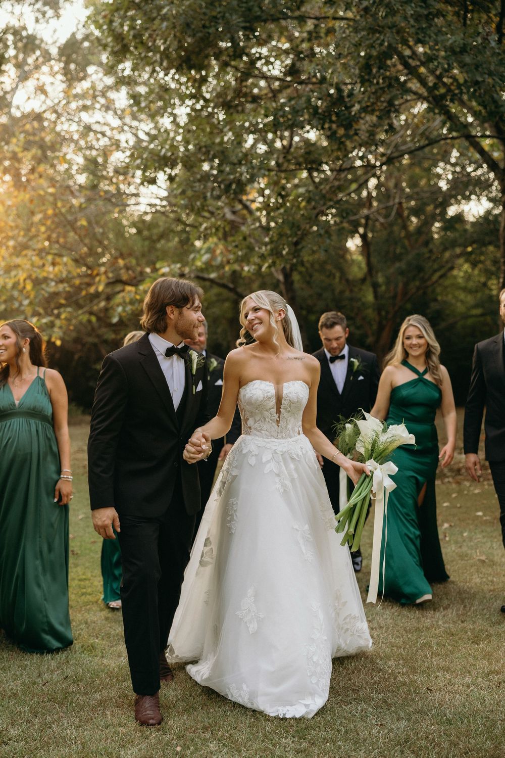 Wedding party in emerald green dresses and black tuxedos together outdoors during golden hour at The Elms of Coosada in Coosada, Alabama