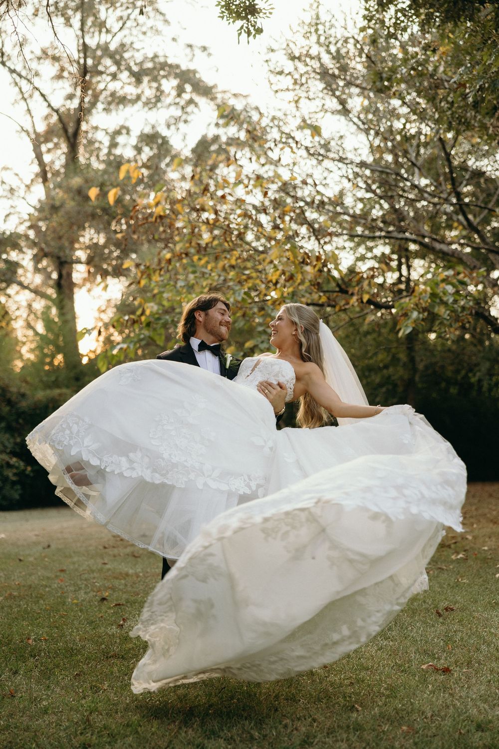 A wedding couple dances and twirls on a grassy lawn at sunset at The Elms of Coosada in Coosada, Alabama