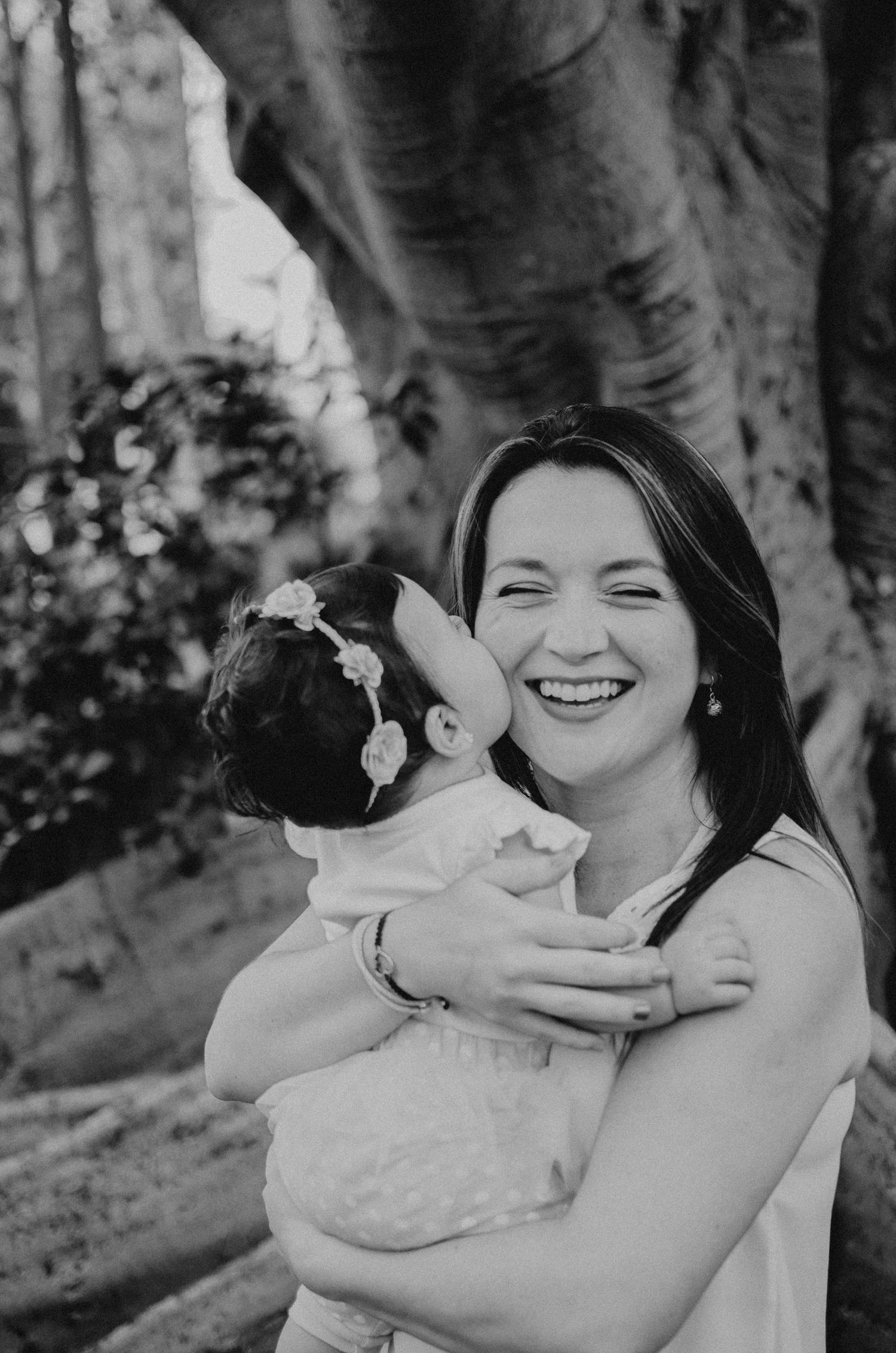 Black and white portrait outdoors by tree trunk.