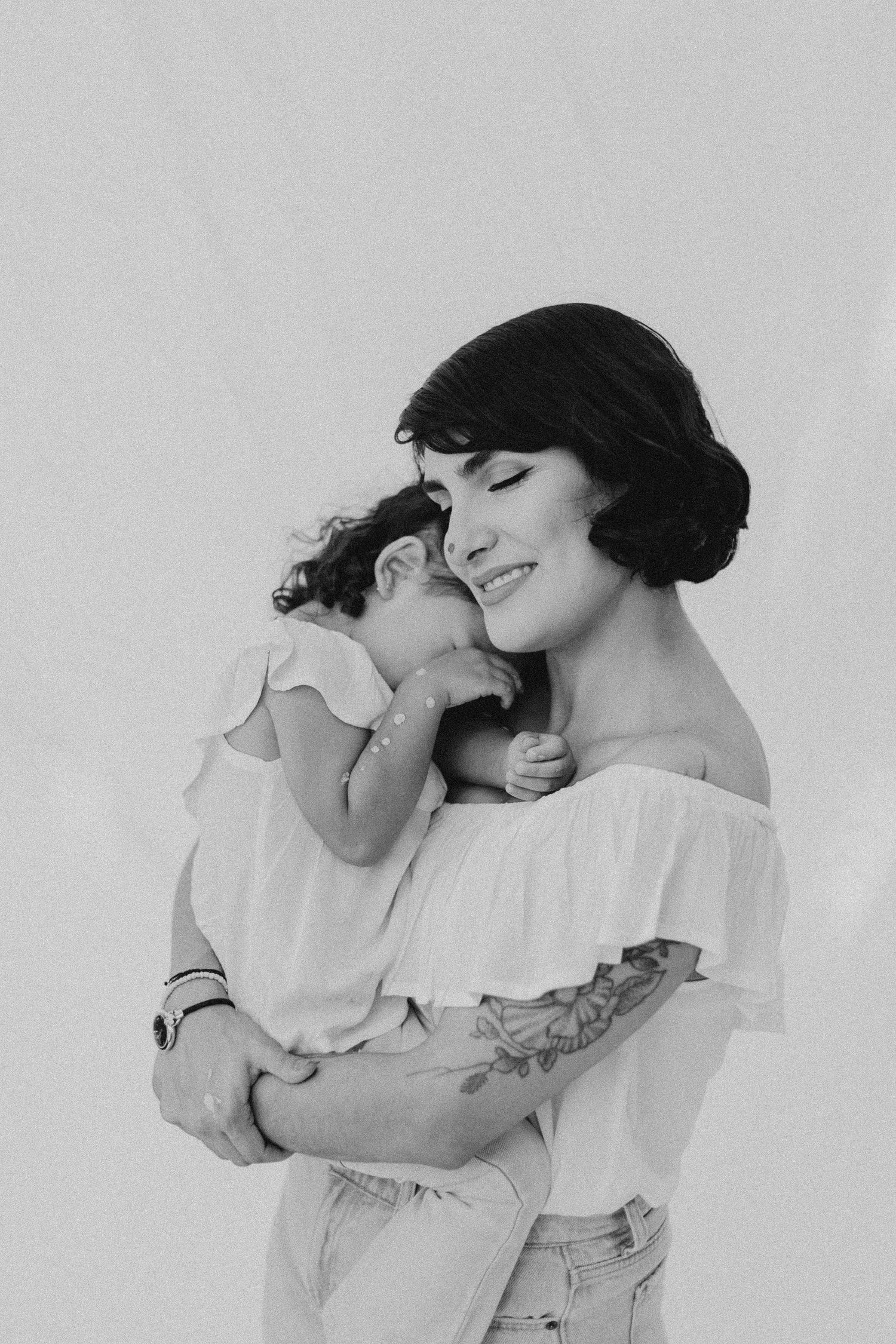 A tender black and white portrait showing an embrace against a light background.