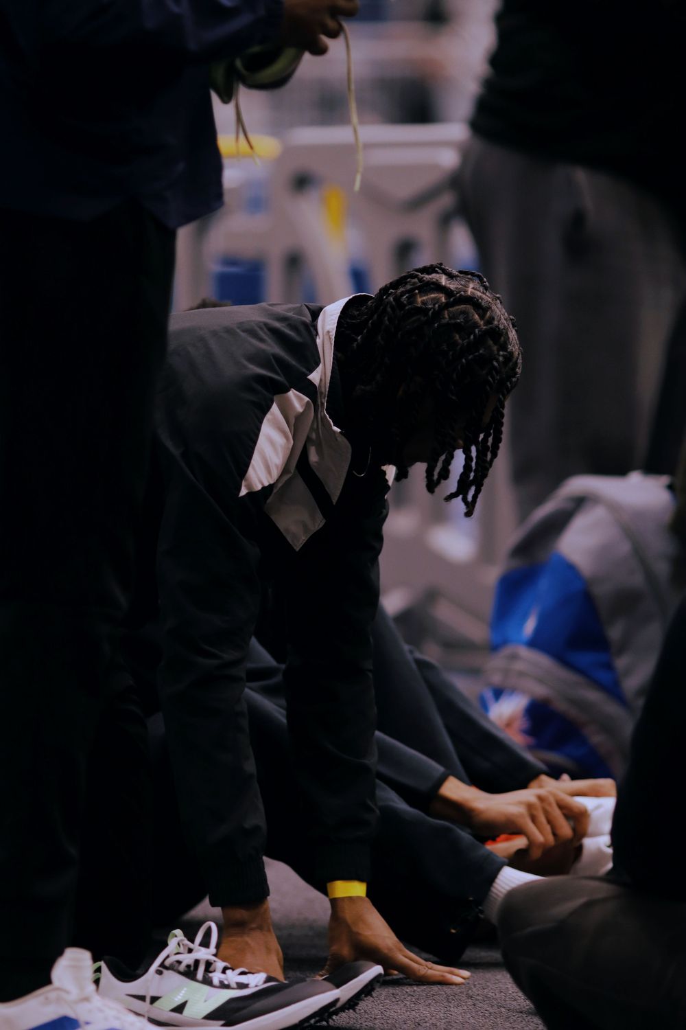 Close-up shot of hands adjusting black and white sneakers in a dimly lit setting.