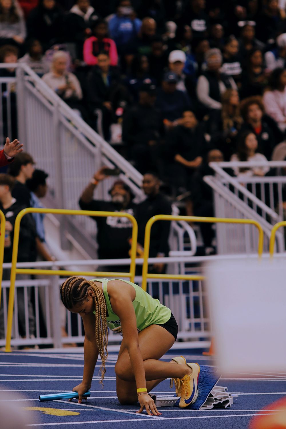 Sequence of images showing a track athlete falling during a race on an indoor track.
